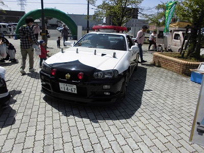 アーチ状のゲート近くに停められたスカイラインの白黒のパトカーの写真