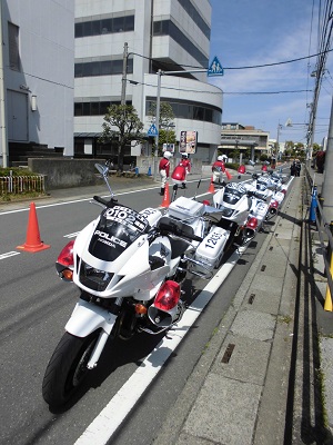 交通整備された道路わきに4台並べて停められている白バイの写真