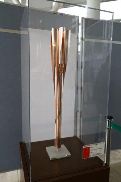 ピンクゴールドの色をした聖火リレートーチがアクリルケースの中に展示されている写真