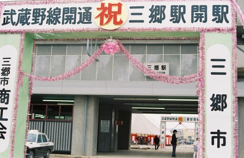 駅の入り口に「武蔵野線開通 祝 三郷駅開駅」と書かれ装飾されたお祝いの看板が設置された三郷駅の写真