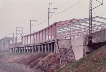 斜面上に組まれた土台上に骨組が建てられているだけの建設中の駅舎の写真