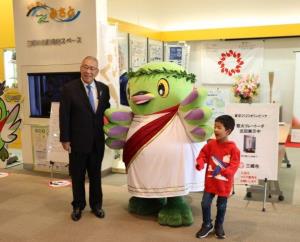 聖火リレートーチが展示されているブースの前で、スーツ姿の木津市長や古代ギリシャの衣装を着たかいちゃんと一緒に記念撮影をしている男の子の写真