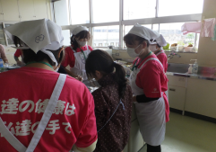 ヘルスメイトのかたが両側から見守る中、女の子が作業をしている様子を後ろから撮った写真