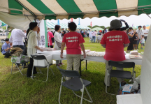 屋外に設置されたテントでイベント来場者の対応をするヘルスメイトスタッフの写真