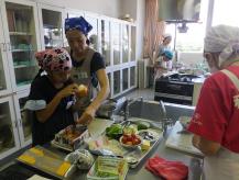 調理室でピンクのバンダナをつけた女の子が食材に集中して作業をしている様子の写真