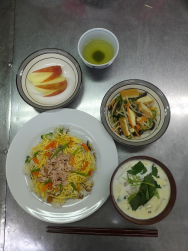 台の上に色とりどりな食材で調理されたおかずや汁もの、ウサギ型にカットされたりんごなどの料理がお皿に盛られ手前にお箸が添えられている写真