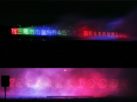 祝民主委員制度100周年とかかれた赤や緑・青色の仕掛け花火の写真