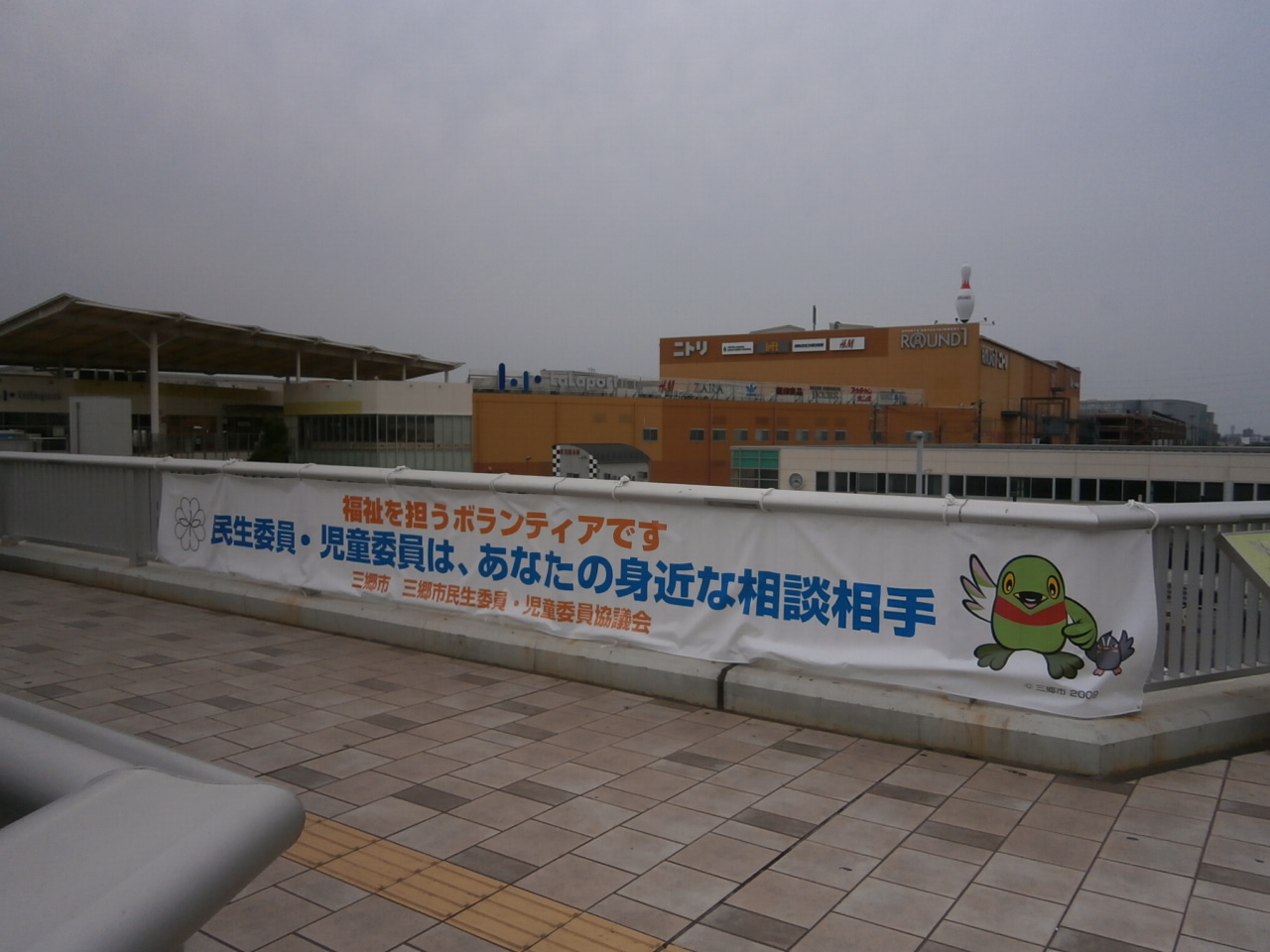 民生委員・児童委員活動PR用横断幕が新三郷駅前ペデストリアンデッキに結ばれている写真