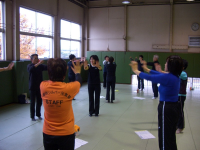 指導者養成講座に参加している人達がグループごとに円になり両手を前にあげて運動をしている様子を写した写真