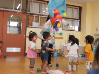 室内で玉入れあそびをする2歳児数名の様子