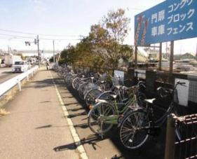 歩道の横にたくさんの自転車が横一列で駐車され、端にフェンスが設置されている鎌倉サイクルアンドバスライドの写真