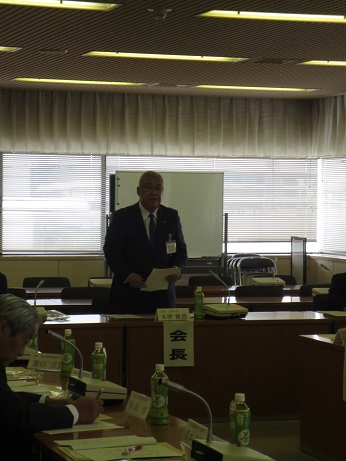 「会長」と書かれた紙が貼られた席から立ち上がり資料を持ち話をしている市長の写真