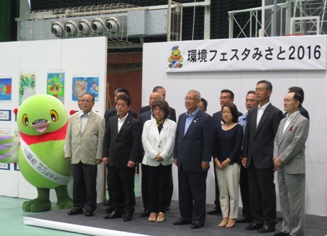 会場の小さなステージ上にマスコットキャラクターかいちゃんと関係者の皆さんが並んでいる記念写真