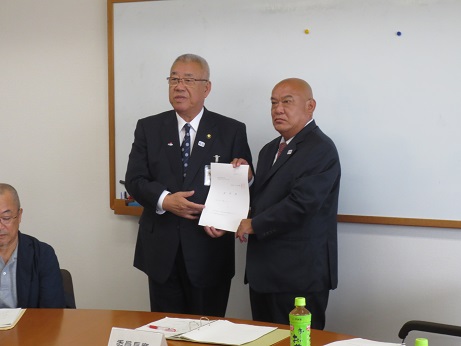 ホワイトボードの前で、三郷市長と関係者の男性が陸上競技場の管理運営に関する事項が記載された諮問書をともに持ち記念撮影をしている写真