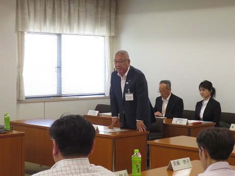 席を立ち挨拶の言葉を述べる三郷市長と席札が置かれた席に座り話を聞く参加者の写真
