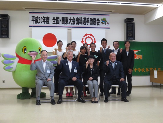 「平成30年度全国・関東大会出場選手激励会」の横断幕が設置されている部屋で、市長が三郷クラブの関係者やかいちゃんと並んで記念撮影をしている写真