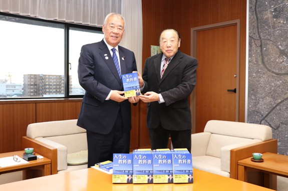 市長と白川好光様が「人生の教科書」の図書を一緒に持って記念撮影をしている写真