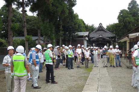 樹木に囲まれた神社の境内に集まっているヘルメットを被った参加者の皆さんの写真