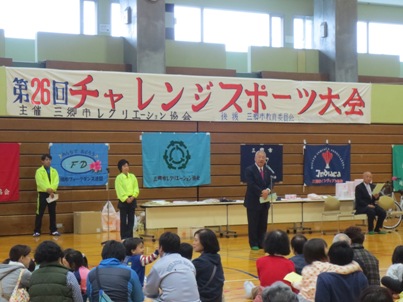 「第26回チャレンジスポーツ大会」と書かれた横断幕の下中央に立つ市長が挨拶を行っている写真