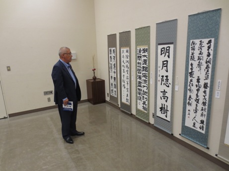 壁に並んで展示されている達筆に書かれた書の作品を立ち止まって鑑賞している市長の写真