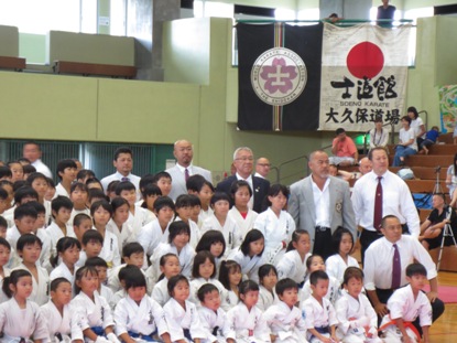 体育館内で、道着を着用した子供たちや指導者と市長が並んでいる記念写真