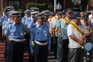 黄色のタスキを肩にかけた関係団体の皆様と警察官の方々が一緒に整列して立っている写真