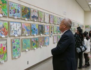 壁に飾られた児童たちが描いた図画の作品を鑑賞している市長の写真