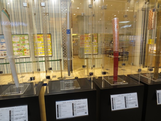 施設内に様々な形の聖火トーチが並んで展示されている写真