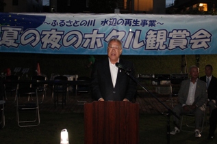 「夏の夜のホタル観賞会」と書かれた横断幕の手前の檀上で挨拶を行っている市長の写真