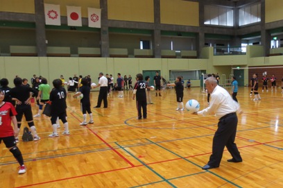 市長がスーツの上着を脱ぎ、白と水色のボールを打とうとしている始球式の様子の写真