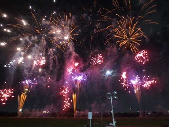 夜空がオレンジ色やピンク、白などの鮮やかな花火で彩られている写真