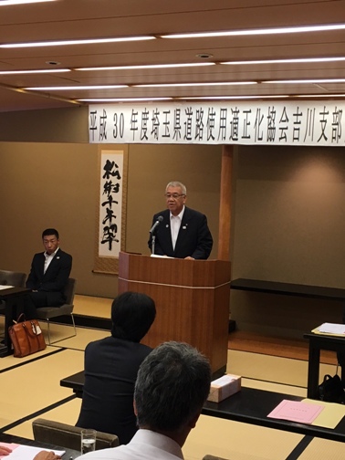 「平成30年度埼玉県道路使用適正化協会吉川支部」の紙が設置された和室で、関係者たちの正面に立って話をしている市長の写真