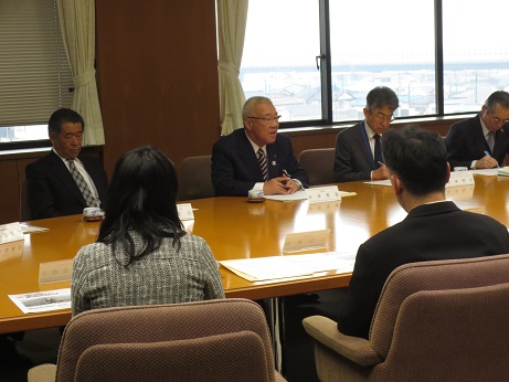 幅広のテーブルに向かい合って座った出席者たちと意見交換をしている市長を正面から写した写真