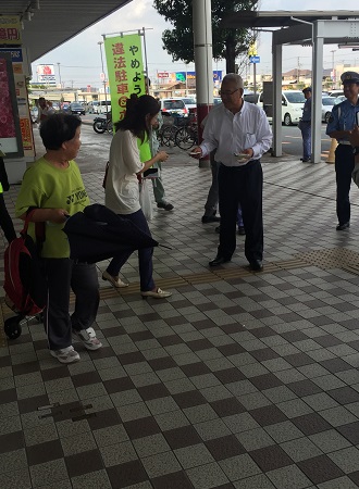 商業施設前の通路で買い物に訪れた女性に市長が啓発グッズを渡している様子の写真
