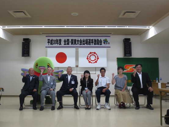 「平成30年度全国・関東大会出場選手激励会」の横断幕が設置されている部屋で、市長が前川中学校の関係者とかいちゃんと共に並んで記念撮影をしている写真