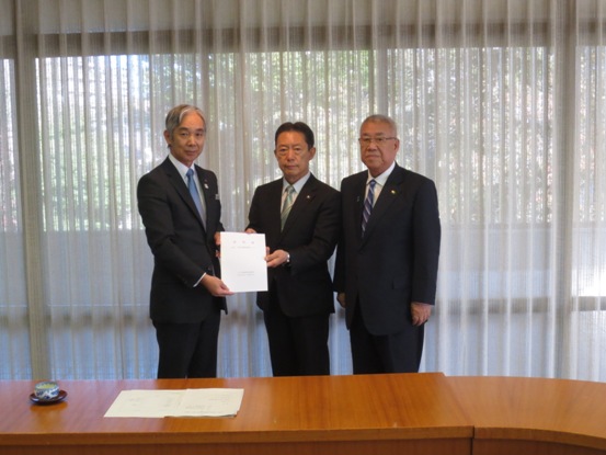 窓に白いレースカーテンが掛かった室内で、要望書を共に持つ飯島副知事、井崎流山市長と、三郷市長が長机の後ろに並んで立っている記念写真