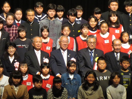 前後列になって並んでいる子供たちと、その中心あたりに座る市長、市長の両側に座る来賓の方たちの集合写真