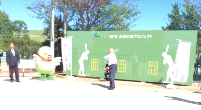 マスコットキャラクターかいちゃんが応援しているなか、市長がベースウォールの前でバットを持ち構えている始球式の様子の写真