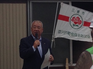 「彦川戸町会自主防災会」と書かれた旗を持って挨拶を行っている市長をアップで撮影した写真
