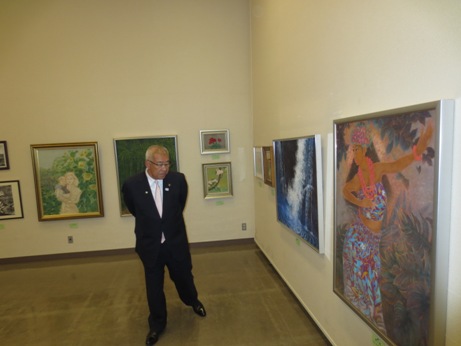 白い壁に展示された大小様々な絵画を鑑賞する市長の写真
