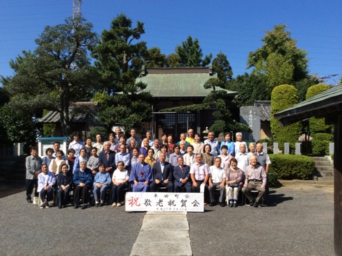 「祝 敬老祝賀会」と書かれた横幕が立てかけられた後ろに市長と三遊亭春馬さんを中央に参加者が並んでいる集合写真