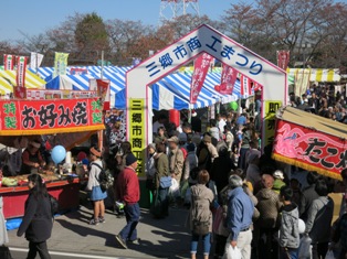 黄色や青色のストライプ柄のテントが並んでいる出店に大勢のお客さんが並んでいる産業フェスタ会場の様子の写真