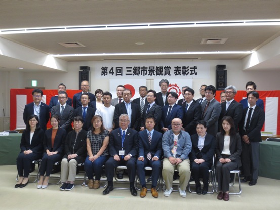 前列の椅子に市長を中央に8名が座り、2列と3列目に受賞者が立っている記念写真