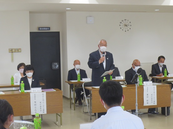 長机が等間隔に設置されている部屋で、多くの関係者が着席しているなか市長が立ってマイクを手に話をしている写真