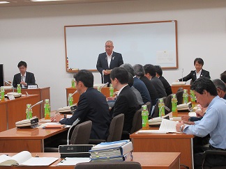 地区協議会で、前に立って話す男性と座って聞く参加者達の協議会の様子の写真