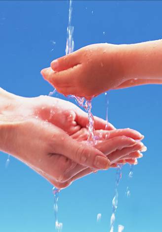 注がれる水を大人の手と子供の手で受ける取っている写真