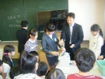 黒板とモニターがある教室で、男性の指導の下、開票作業をしている児童たちの写真