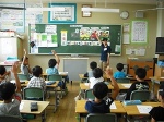 小学校の教室で、栄養教諭に小学生の子供が、4人手を挙げて質問している写真。