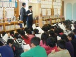 前方に立ち説明している2名の男性と、手元の資料を見ながら説明を受けている児童たちの写真