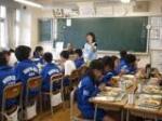 中学生の給食の時間に栄養教諭が教壇に立ち食育指導をしている写真。